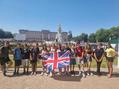 Imagine1world students with the British flag in front of Buckingham Palace